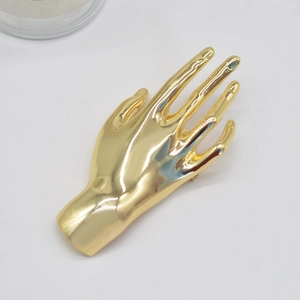 Macro shot of a hand-shaped gold metal brooch with a smooth polished texture for suits