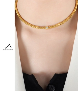 Macro shot of gold plated stainless steel choker with round zircon pendant on neck