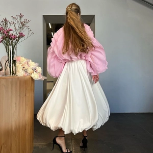 Detail van roze organza top met witte satijnen ballonrok en een gouden CD-haarklem