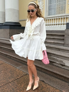 Detail of V-neck ruffled neckline and tiered skirt on white chiffon mini dress