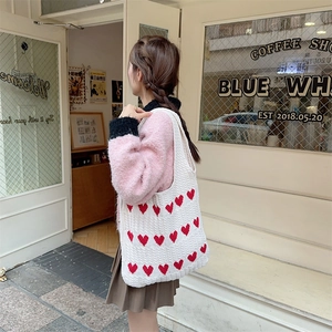 Detailed knit texture of white tote bag featuring red heart patterns and soft cotton yarn