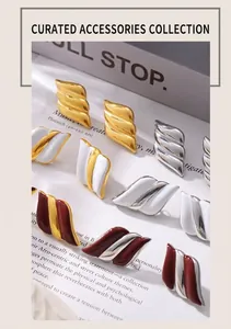 Close-up of geometric 18k gold plated wing studs in multiple colors on a grey background