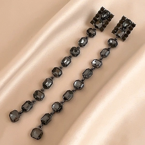 Detailed macro view of black rectangular crystal tassels on elegant champagne silk fabric