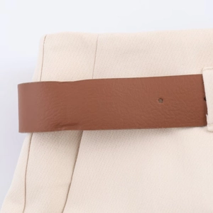 Detail of beige fabric texture with a brown faux leather belt and stitching on pants