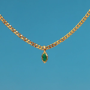 Close-up of gold chain link with green marquise-cut zircon pendant on blue background