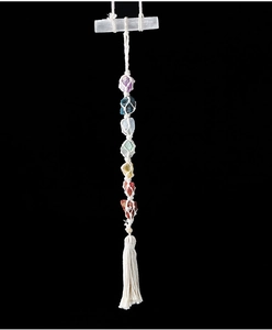 Dettaglio di sette cristalli chakra grezzi e bastoncino di gesso con nappa in cotone bianco