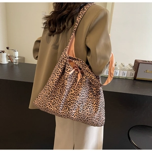 Close-up of leopard print shoulder bag with tie detail on a model in a cafe