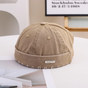 Detail of khaki cotton miki hat featuring a superior metal plate and frayed edge texture