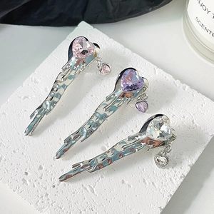 Minimalist liquid metal bow hair clips with heart crystals on stone background
