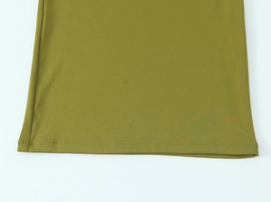 Dettaglio dell'orlo di un abito lungo in maglia verde oliva con cuciture doppie di precisione