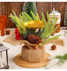 Christmas candle holder detail with red berries pine cone and burlap base on straw mat