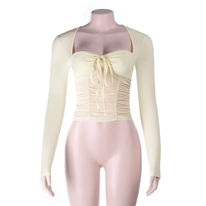 Detail of drawstring ruching and tie-up design on a cream long sleeve cropped top