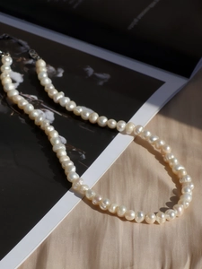 Close-up of elegant freshwater pearl necklace with lustrous white pearls on silk fabric