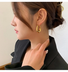 Close-up of a model wearing high-polish gold teardrop earrings in a sleek minimalist style