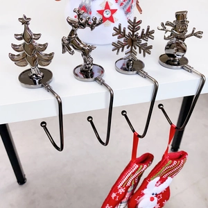 Detail of four metal Christmas stocking hooks with snowflake, reindeer, tree and snowman shapes