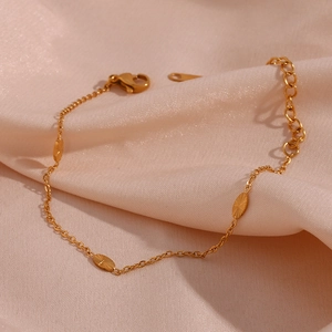 Detail of 18K gold plated chain with textured oval charms on elegant champagne satin