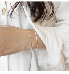 Detail of minimalist S925 sterling silver double-layer bracelet set on a female wrist