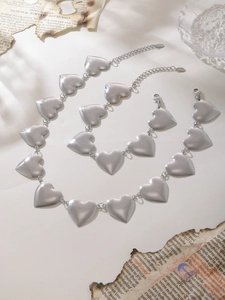 Conjunto de collar y pulsera de cadena con corazón de plata sobre papel vintage