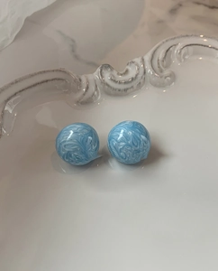 Gros plan de boucles d'oreilles boules en marbre bleu sur un plateau en céramique