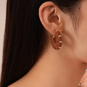 Close-up of brown suede hoop earrings with golden beads worn on ear for detail
