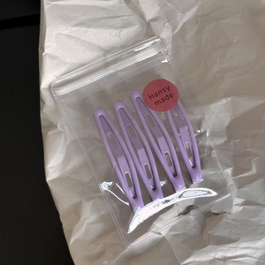 Set of four purple enamel water drop hair clips in a branded transparent gift bag