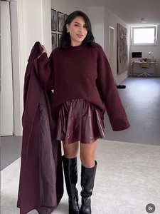 Vue complète d'une femme portant un pull en maille bordeaux avec une mini-jupe en cuir assortie