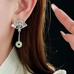 Close-up of fan-shaped silver earrings with green jade stones on a model