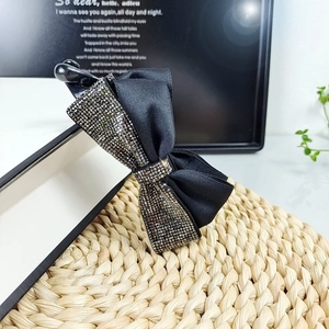 Fermaglio a banana vintage nero con fiocco e strass su un supporto intrecciato