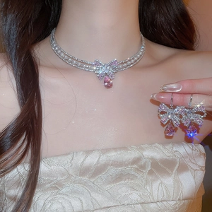 Detailed view of silver bow necklace and earrings set with pink teardrop gemstones