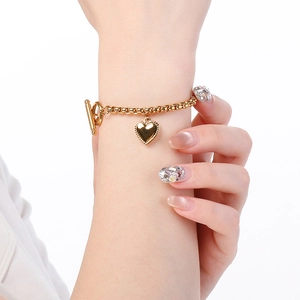 Dettaglio del bracciale in acciaio dorato con ciondolo a cuore e chiusura a barra a T