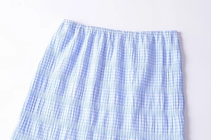 Detail of light blue gingham skirt featuring elastic waistband and crinkle texture fabric