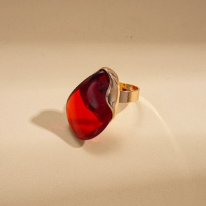 Détail macro d'une grande bague dorée ornée d'une pierre rouge translucide en forme de poire