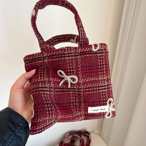 Détail d'un sac à main rétro en laine à carreaux rouges avec un nœud blanc tricoté
