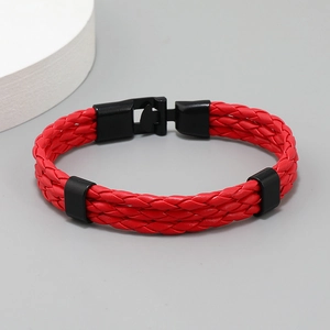 Detail of red braided multi-layer leather bracelet with black metal clasp on a plain background
