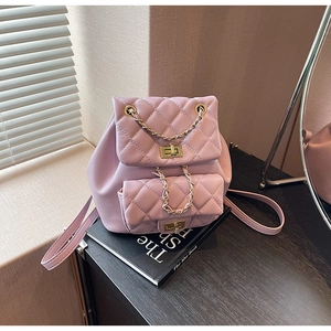 Detail of light pink quilted mini backpack with golden chain and twist lock on books