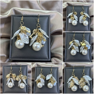 Detail of French vintage gold earrings with pearls, flowers, and key charms on silk