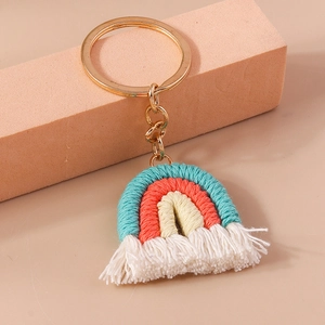Detailed macro view of handmade woven rainbow keychain with white cotton tassels and gold ring