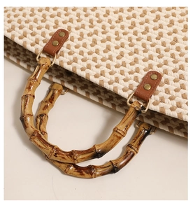 Close-up of bamboo handle and metal buckle on woven tote bag with herringbone pattern