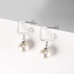 Detail of silver C-shaped pearl drop earrings with butterfly backing and polished finish