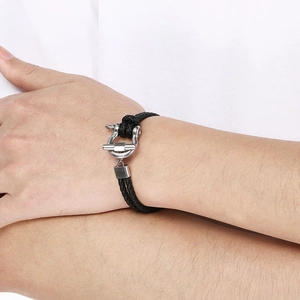 Detail of black braided leather bracelet with silver horseshoe shackle clasp