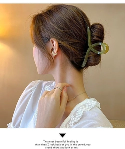 Gros plan d'une grande pince à cheveux vert herbe dans un chignon sur une mannequin