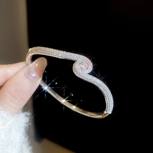 Macro shot of silver S-curve bracelet with cubic zirconia and central round diamond