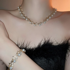 Close-up of gold leaf vine necklace and bracelet set with pearls and rhinestones