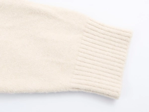 Gros plan du poignet d'un cardigan beige montrant la texture côtelée et le tricot doux