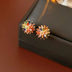Macro view of gold flower stud earrings with colorful rectangular zircons and a center pearl