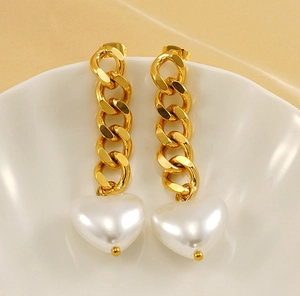 Detail of 18K gold-plated chain earrings with heart pearl pendants on a white bowl