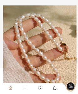Detailed macro view of baroque pearl necklace with gold clasp held by a hand