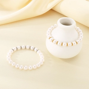 Elegante witte parelarmband met goud en zilveren tussenkralen op een crème zijden stof
