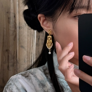 Close-up of vintage hollow geometric gold earrings with pearls on model ear