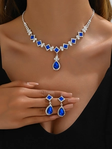 Close-up of blue teardrop pendant necklace and matching earrings on female model